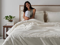 happy girl in ivory bedding with embroidery on it